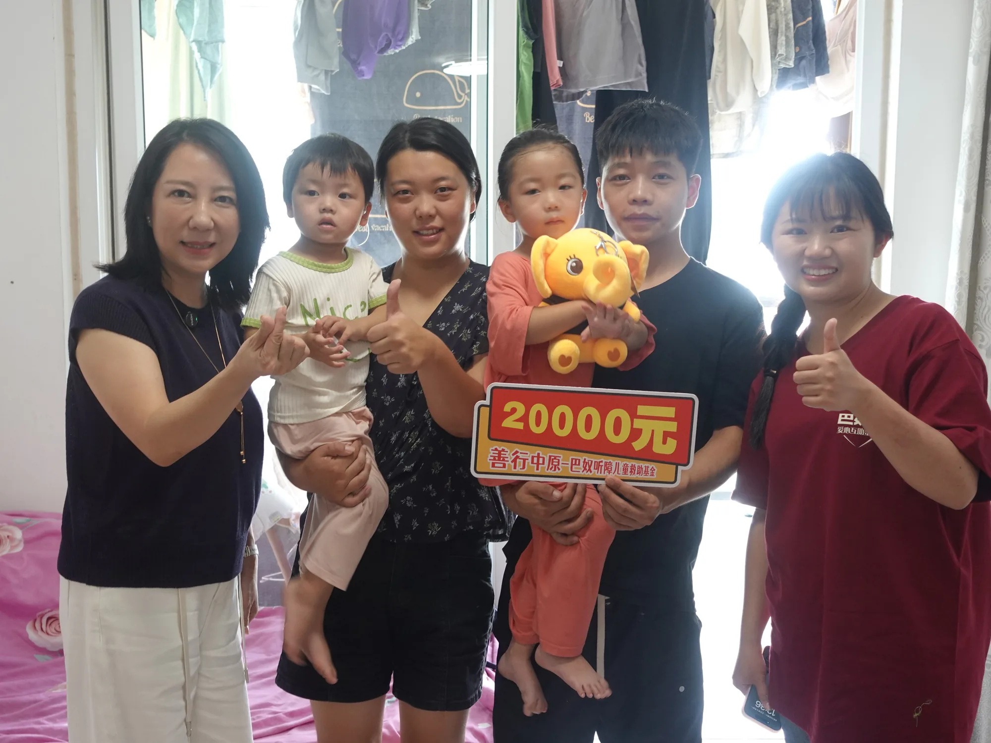 家长抱幼儿与小象暖暖公仔，手持救助牌