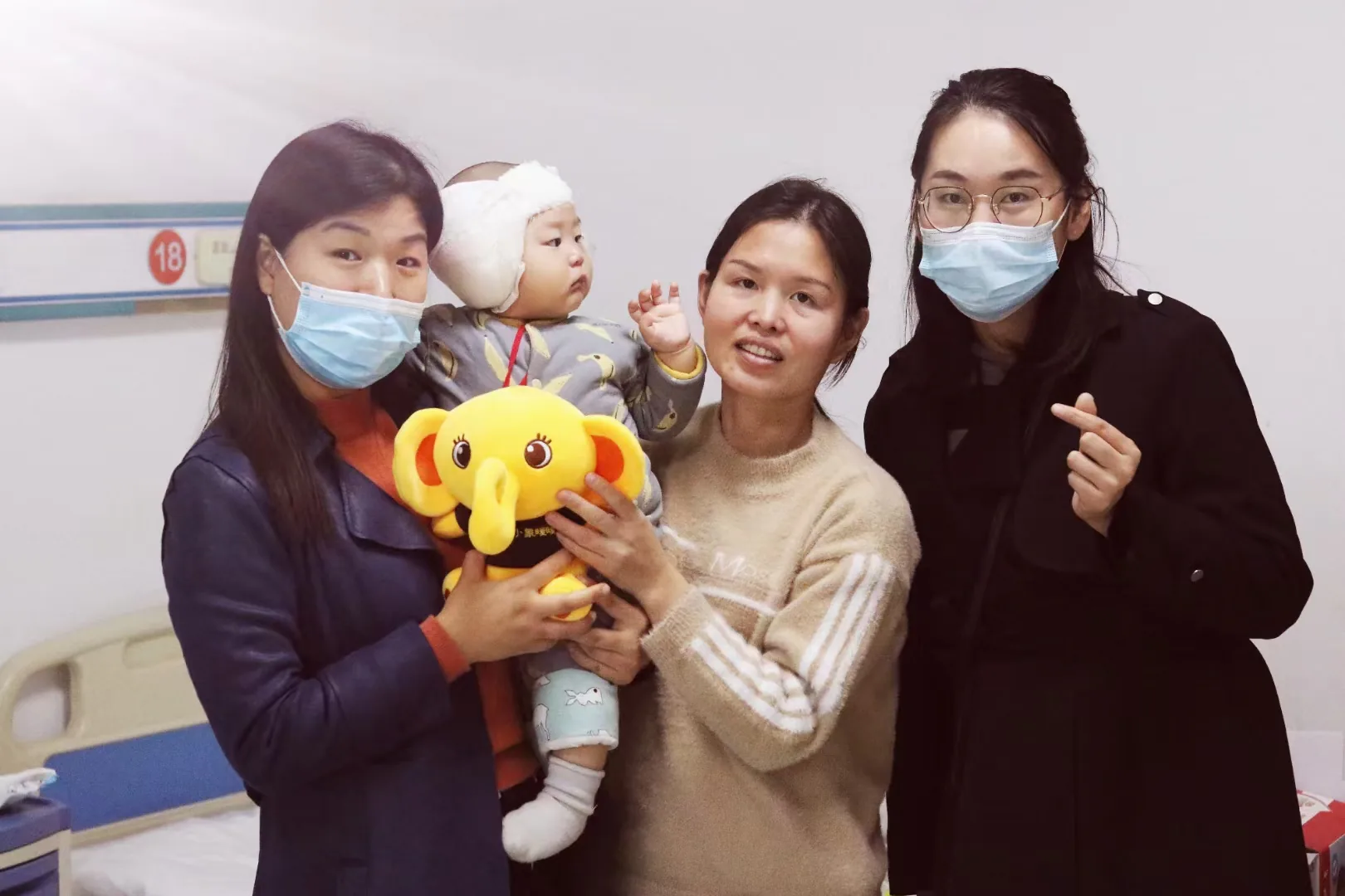 成人怀抱幼儿，手持小象暖暖毛绒公仔