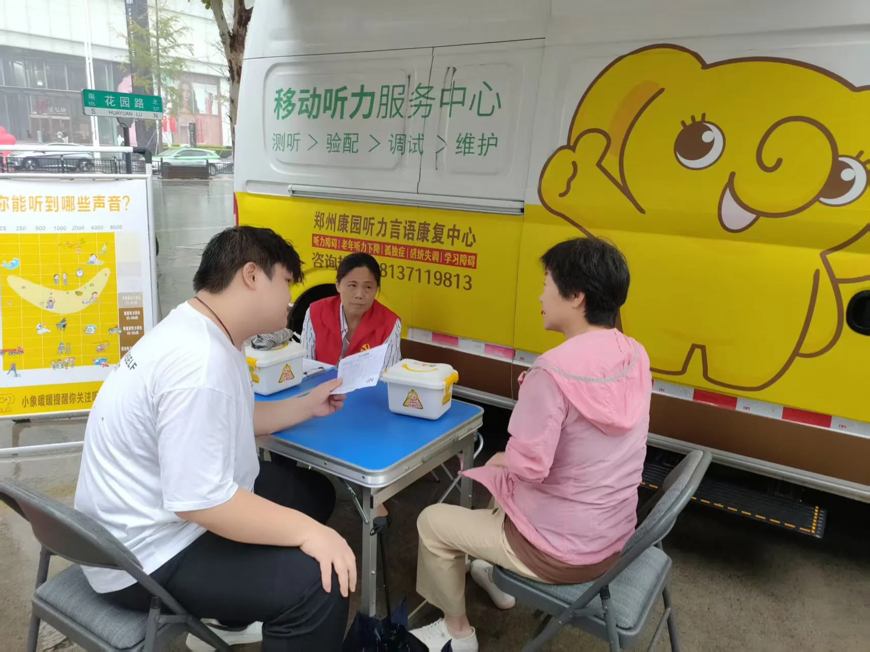 工作人员在移动听力服务车旁为居民登记服务